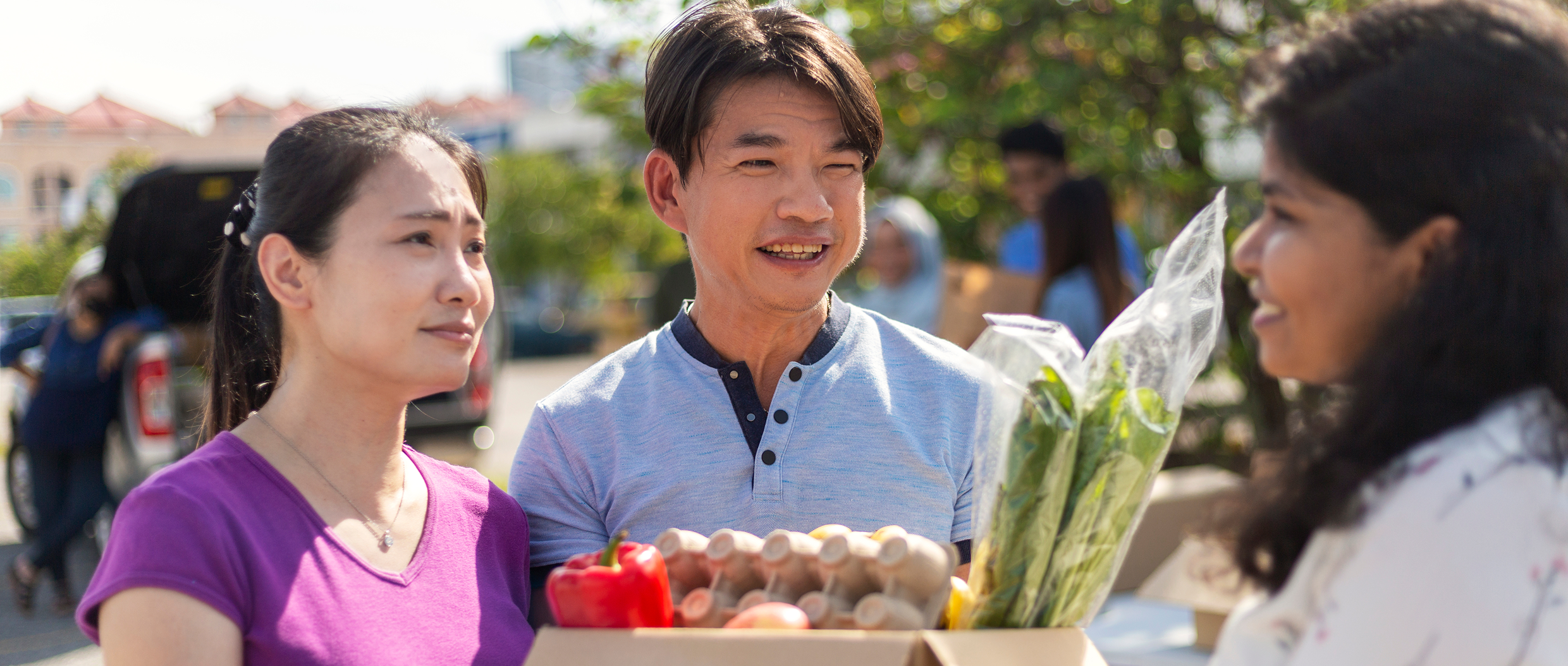 People holding groceries, talking outdoors.