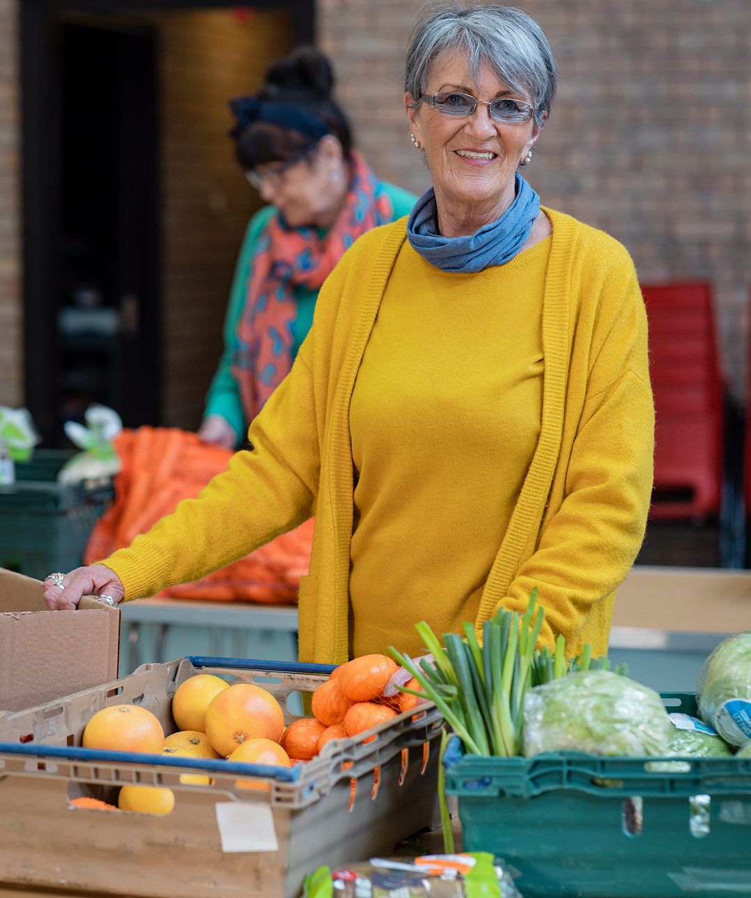 Woman smiling at a vegetable market stall.