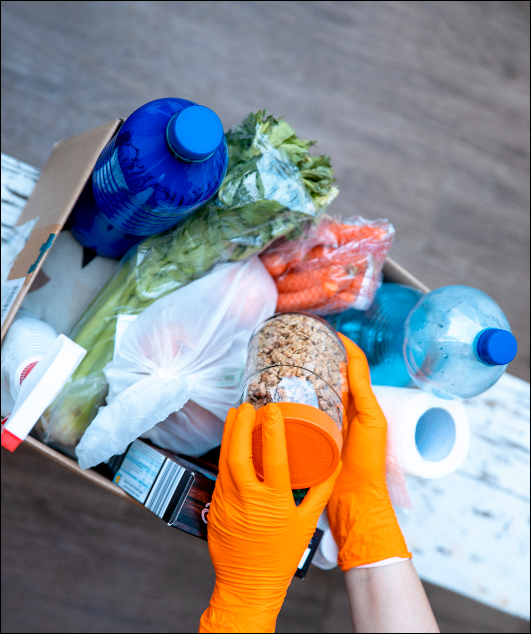 Gloved hands inspecting food items in box.