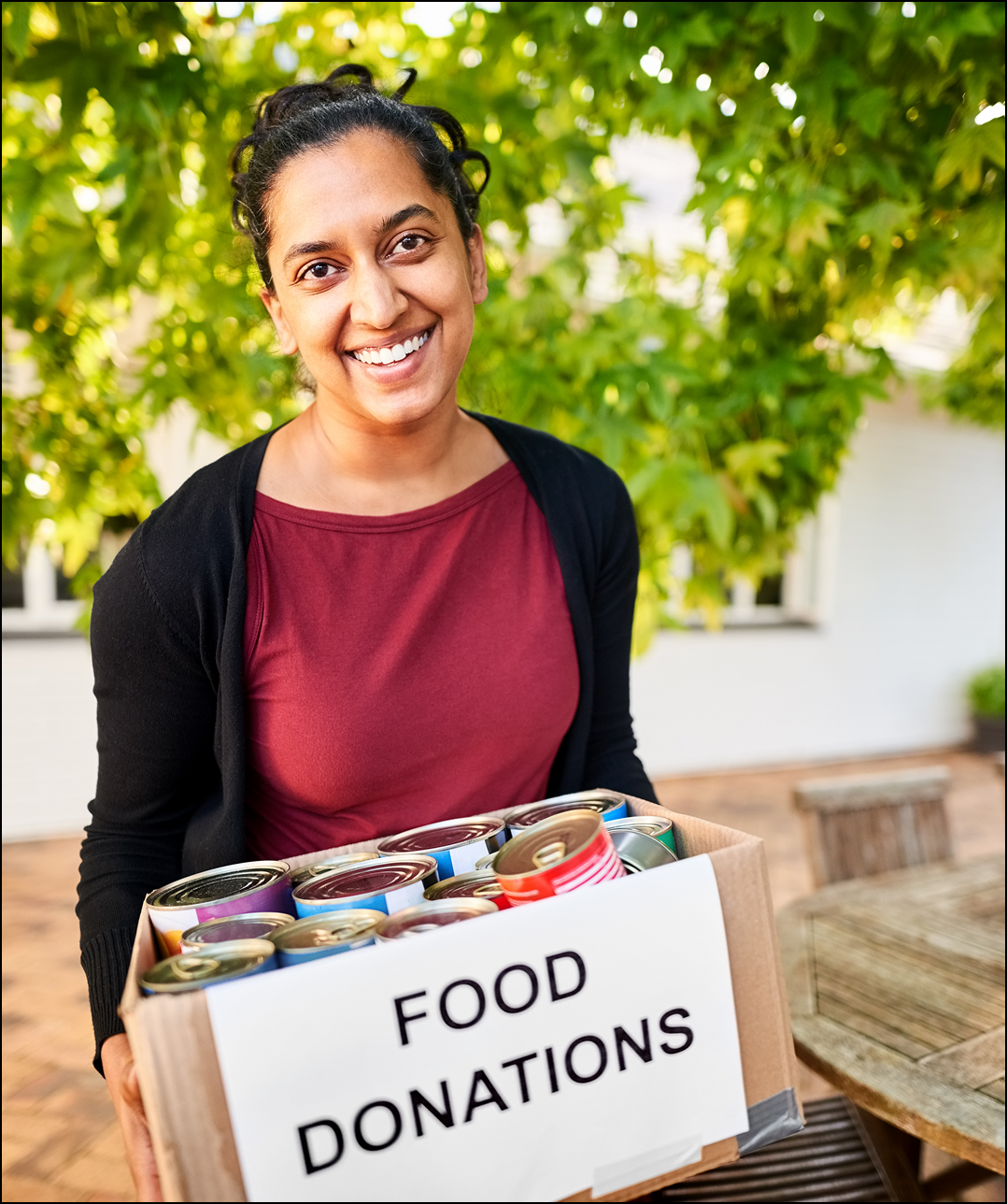Smiling person holding a food donations box.