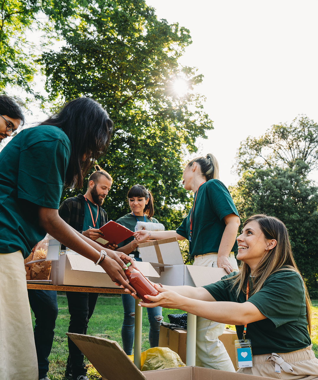 Volunteers organizing donations outdoors in sunlight.
