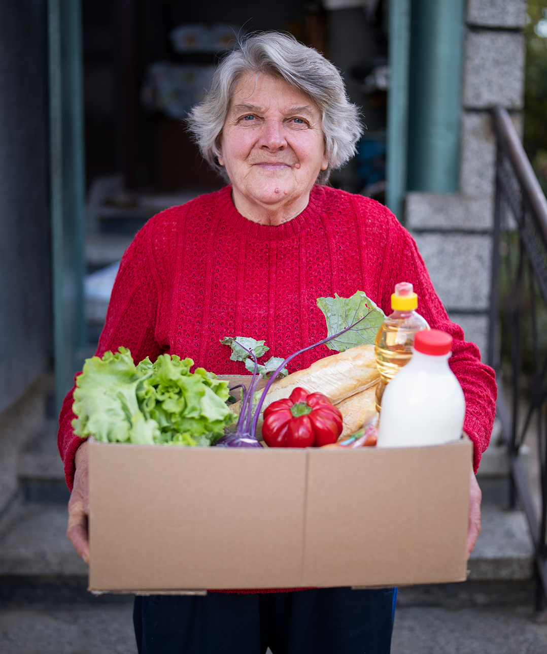 Elderly woman holding a box of groceries.