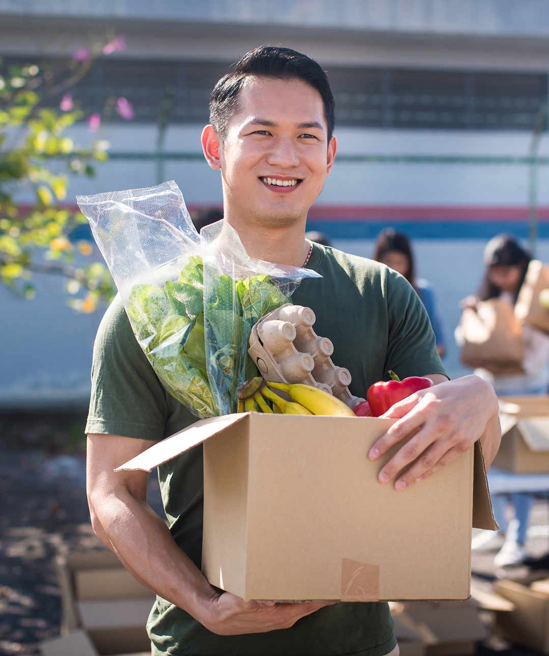 Man holding box of fresh produce outdoors.