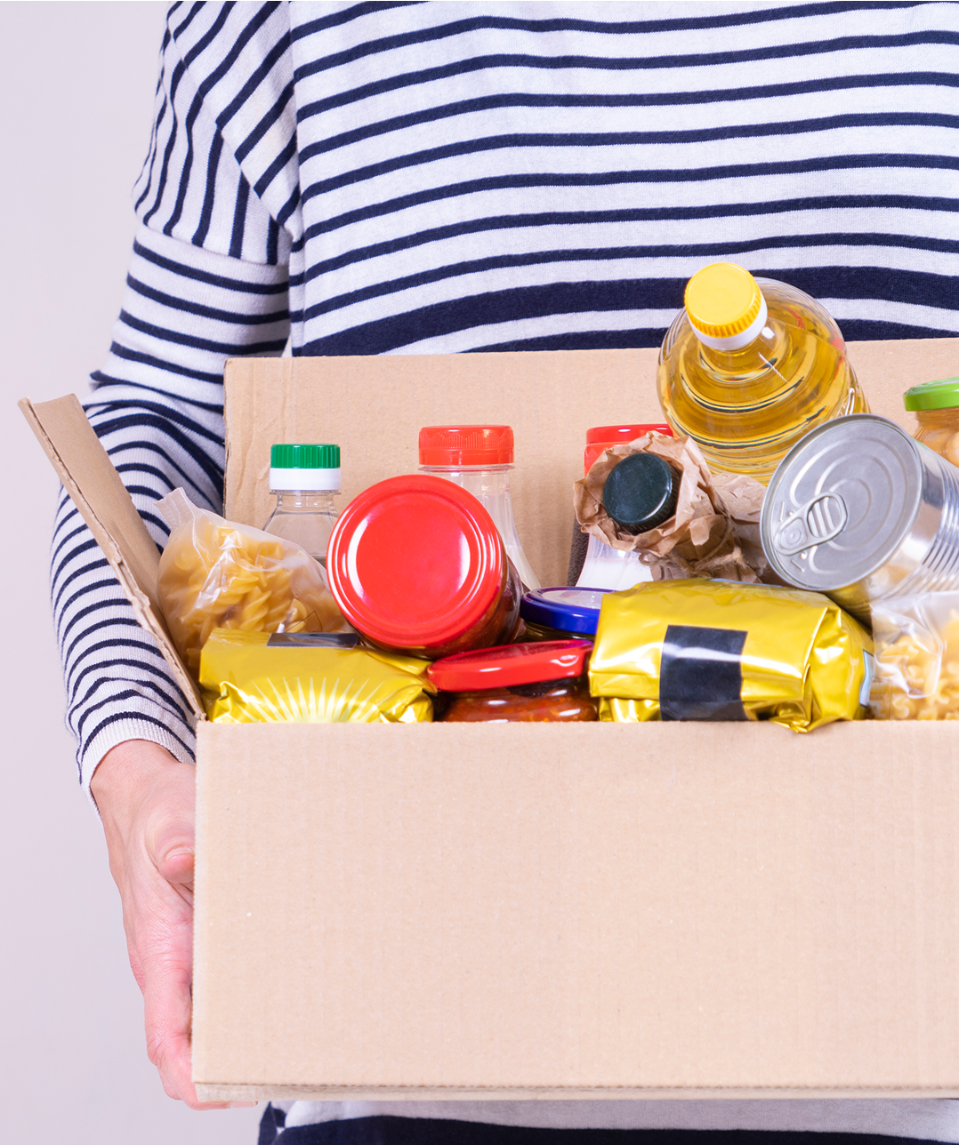 Person holding box of assorted food items.